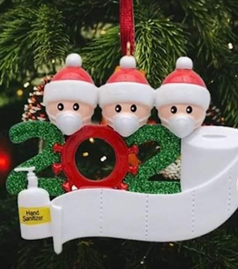 Christmas decorstion showing 3 faces wearing masks and santa hats stood behind the number 2020, the last 0 being a toilet roll